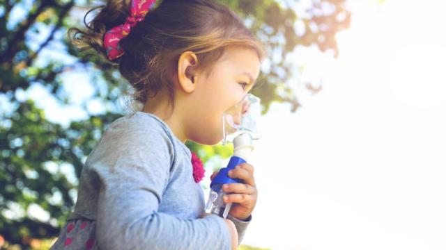 Una niña con asma con un broncodilatador para poder respirar