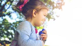 Una niña con asma con un broncodilatador para poder respirar