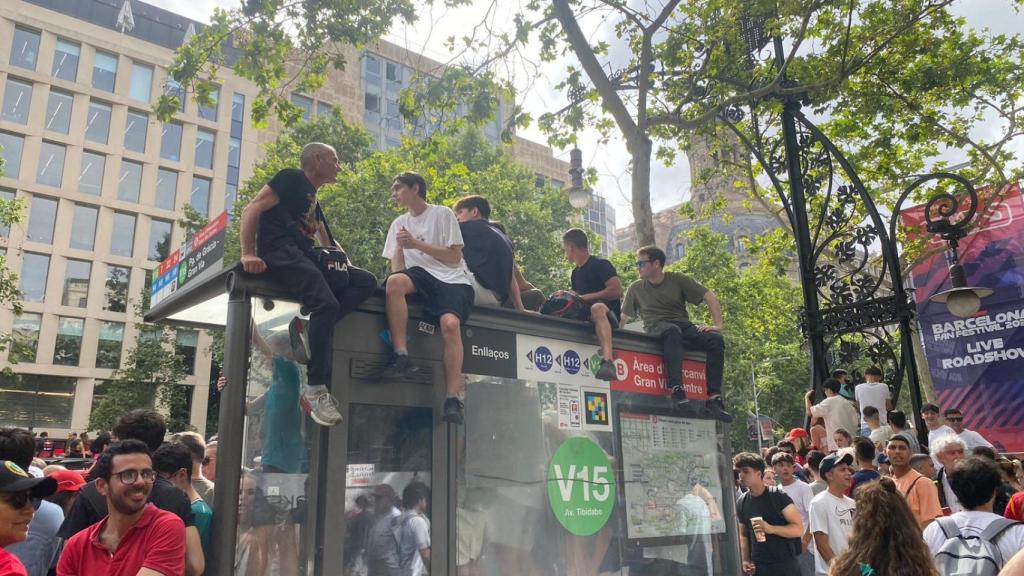 Jóvenes subidos a una marquesina de autobuses en el paseo de Gràcia