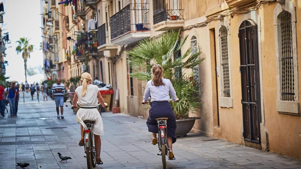 Dos personas en bicicleta por el barrio de la Barceloneta