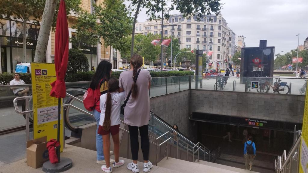 Una informadora explica a dos personas el corte en la L2 del metro de Barcelona