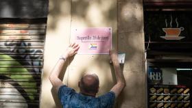 El presidente del Observatori contra la LGTBIfobia, Eugeni Rodríguez, cuelga un cartel en una pared de la 'supermanzana' de Sant Antoni.