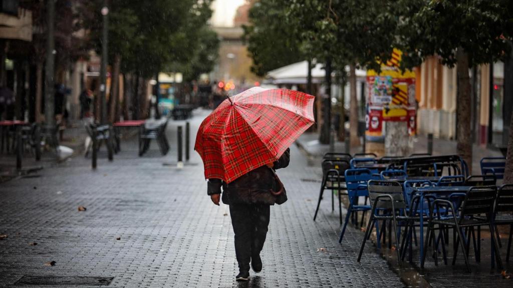 Una persona camina con un paraguas en Barcelona