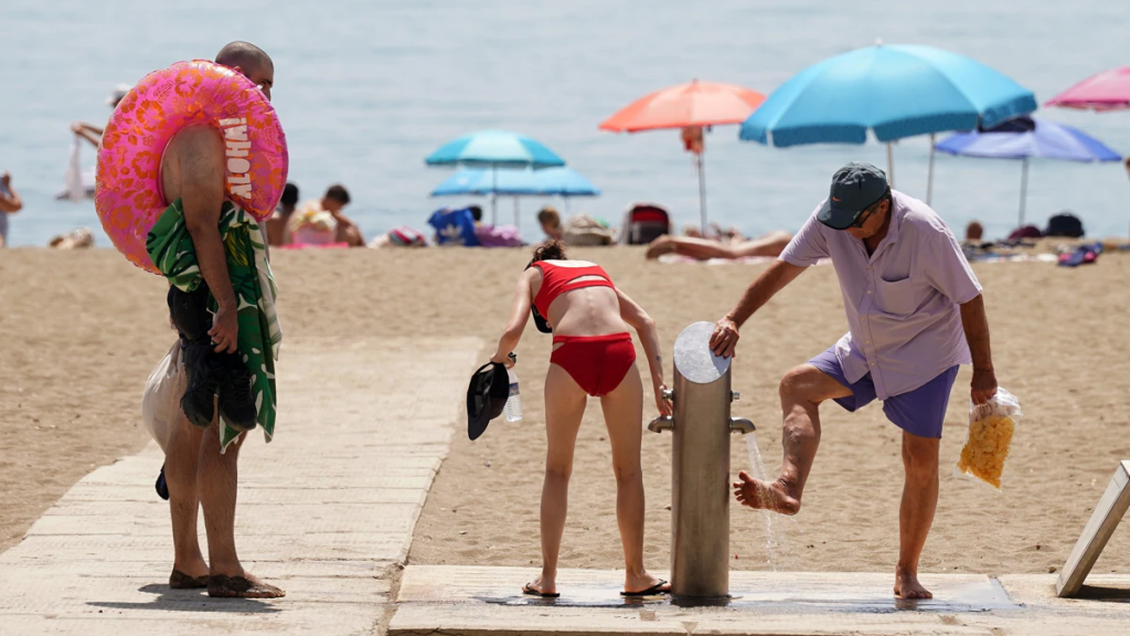 Bañistas haciendo uso de los lavapiés en una playa