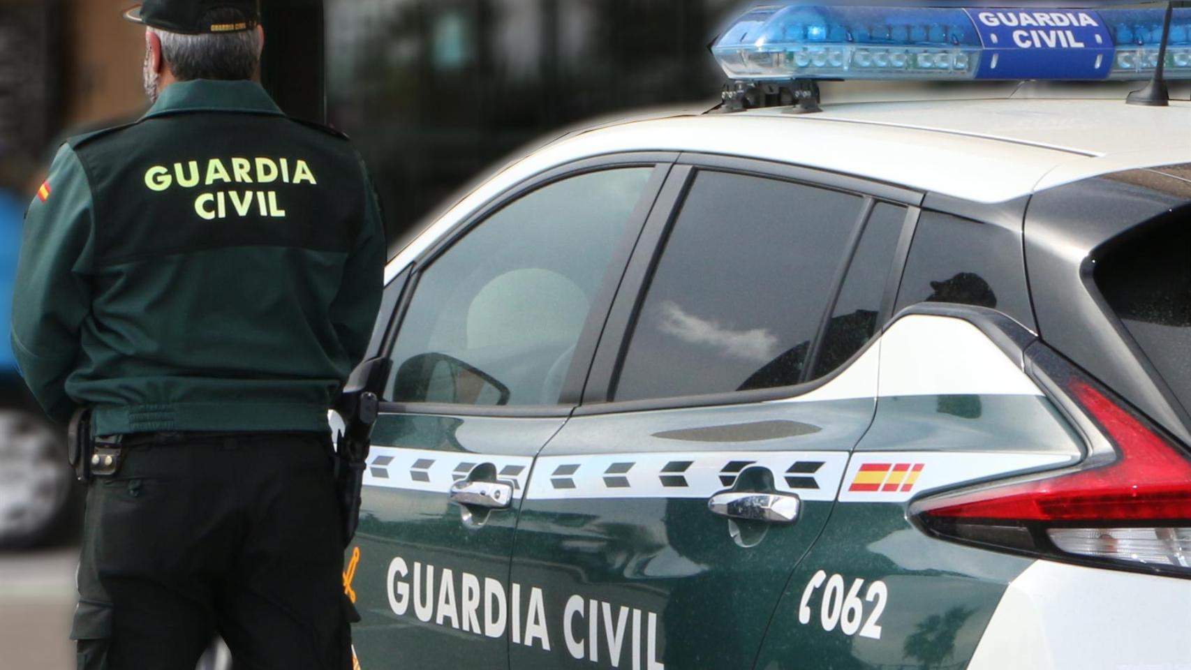 Un agente de la Guardia Civil, de espaldas, junto a un vehículo oficial