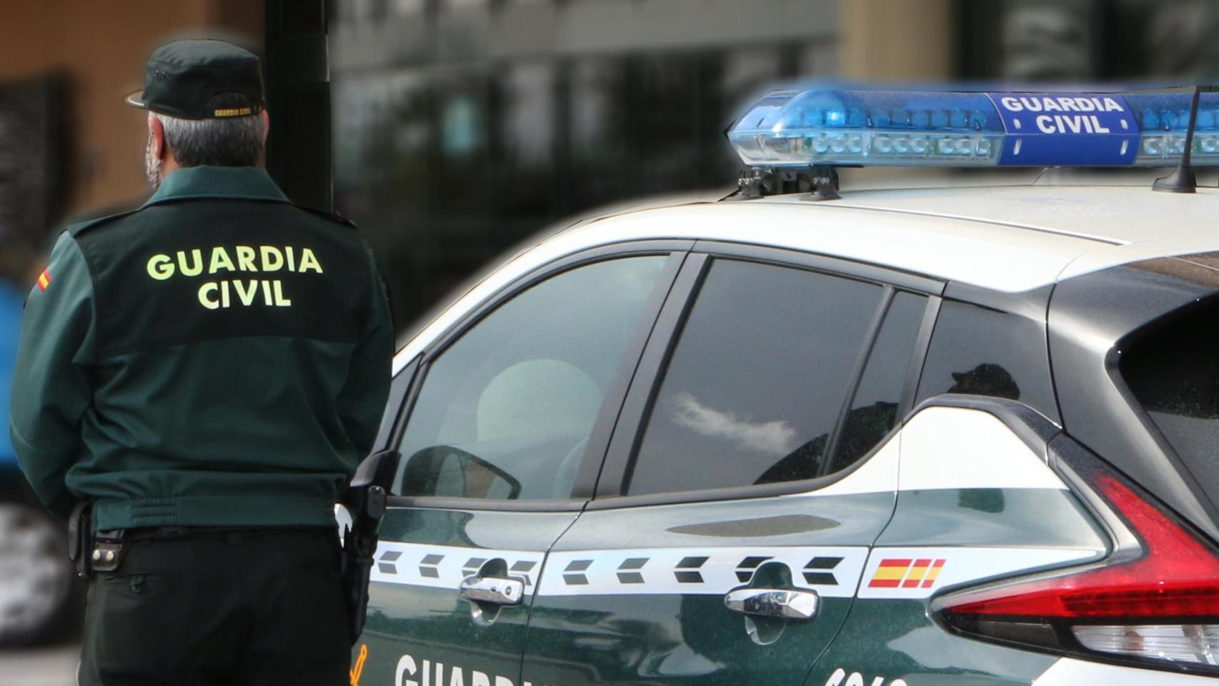 Un agente de la Guardia Civil, de espaldas, junto a un vehículo oficial