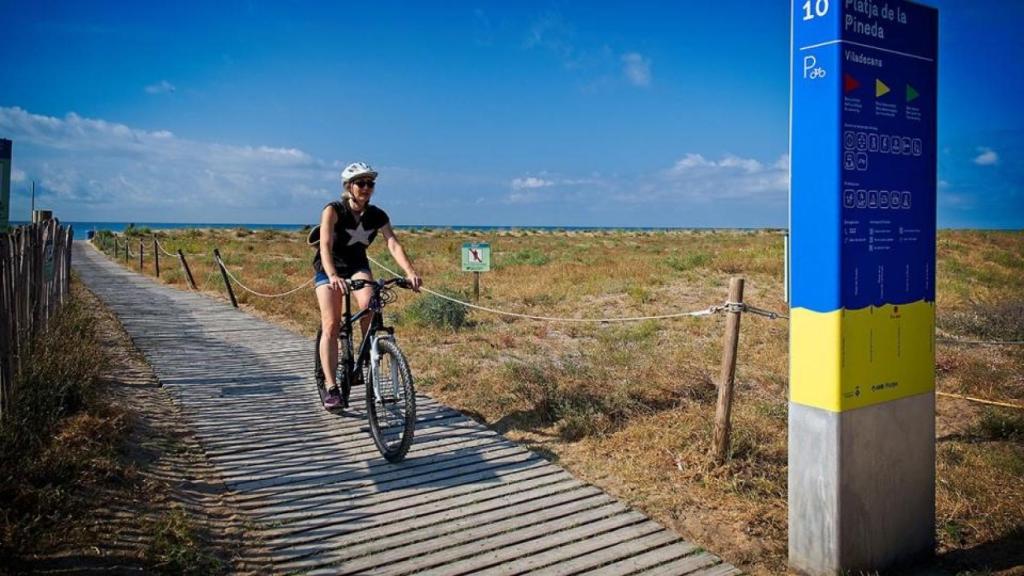 Una mujer en bici en la playa de la Pineda de Viladecans