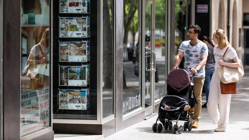 Una pareja observa los anuncios de viviendas en venta en una inmobiliaria