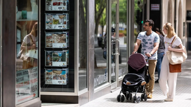 Una pareja observa los anuncios de viviendas en venta en una inmobiliaria