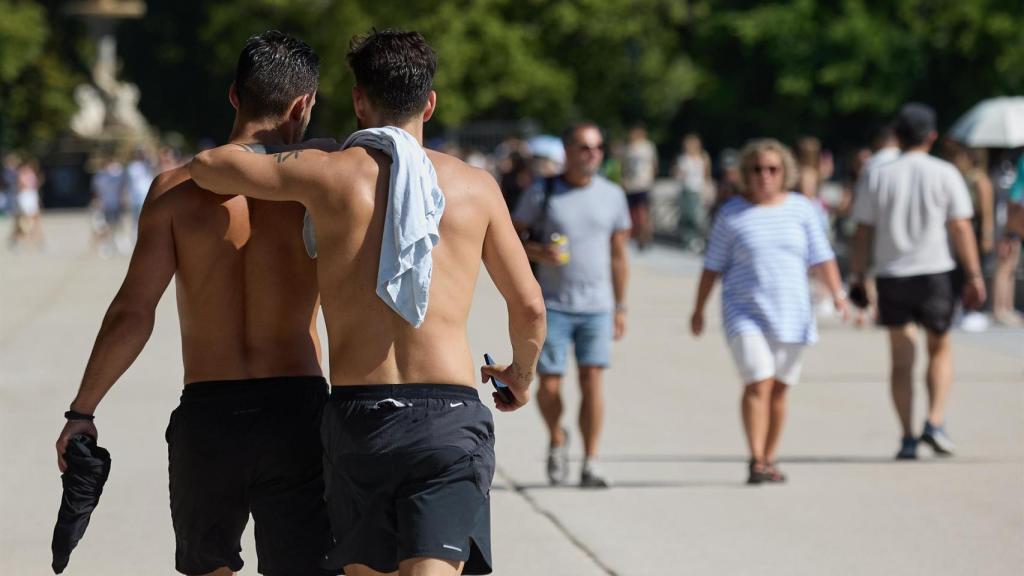 Dos hombres sin camiseta pasean por Barcelona durante la ola de calor