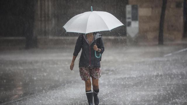 Una persona se resguarda de la lluvia en una imagen de archivo