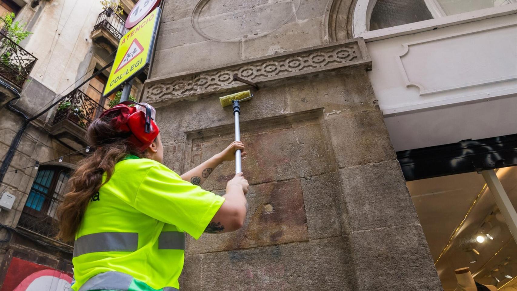 Una operaria limpia una pintada en Barcelona