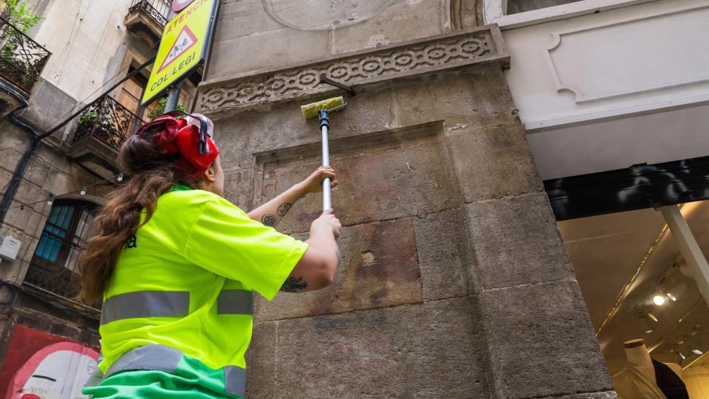 Una operaria limpia un grafiti en Barcelona