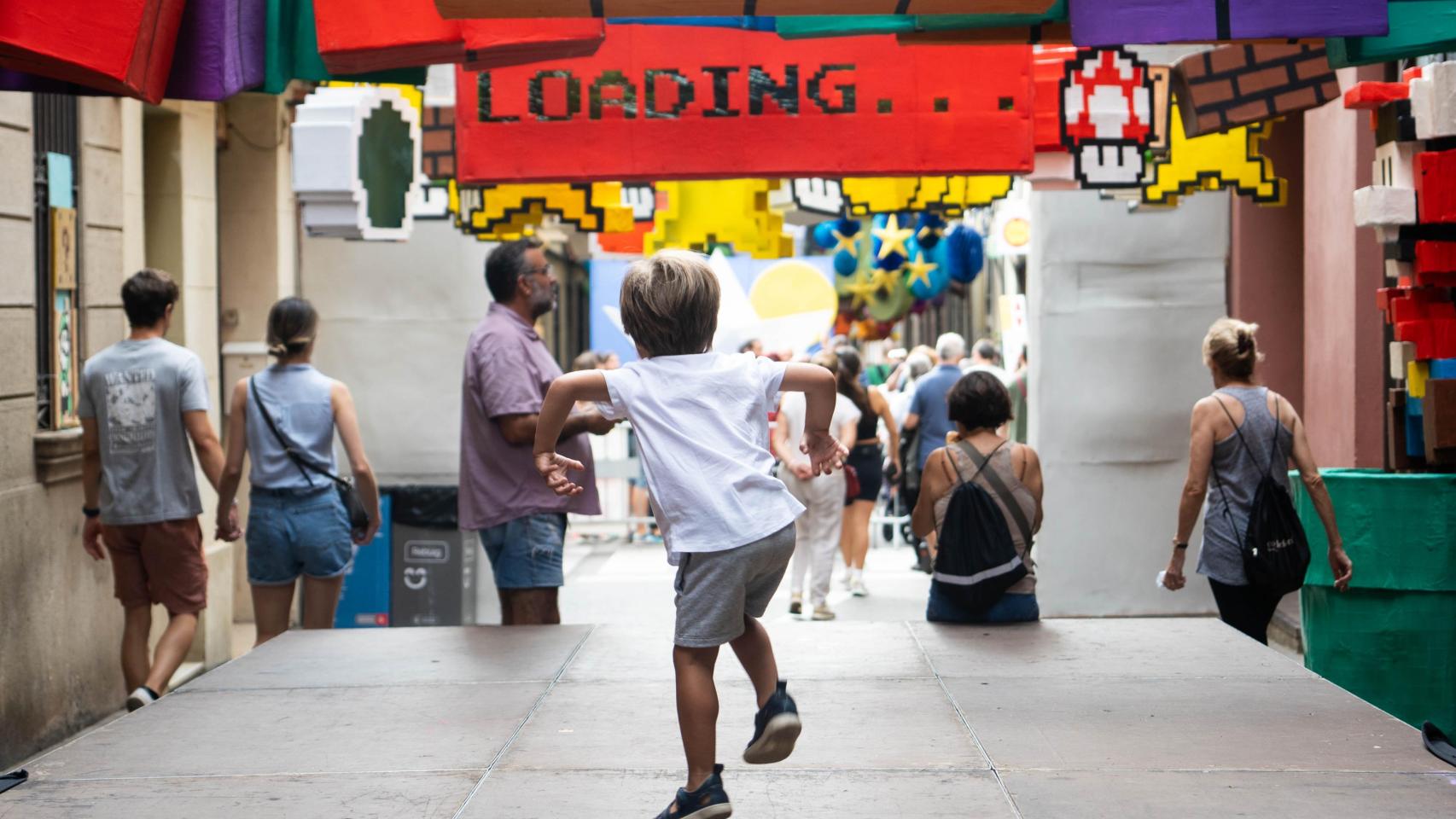 Un niño salta y juega en una calle decorada del barrio de Gràcia 2024