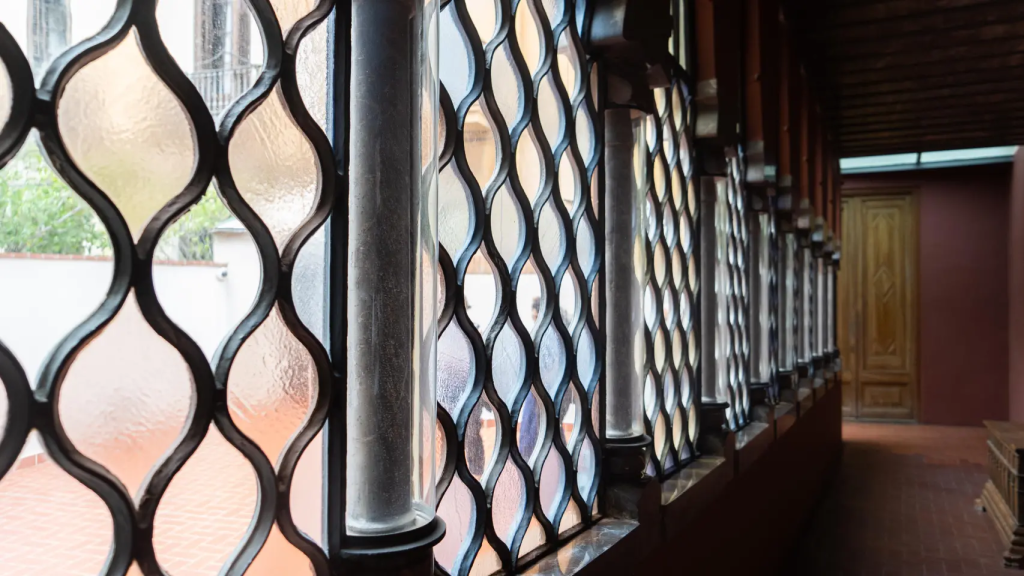 Pasillo interior del Palau Güell con ventanas protegidas por estructuras de hierro forjado