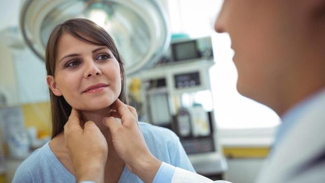 Un especialista palpa el cuello de una paciente