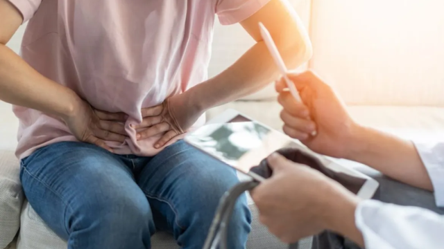 Una mujer explica al médico que siente dolor abdominal