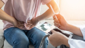 Una mujer explica al médico que siente dolor abdominal