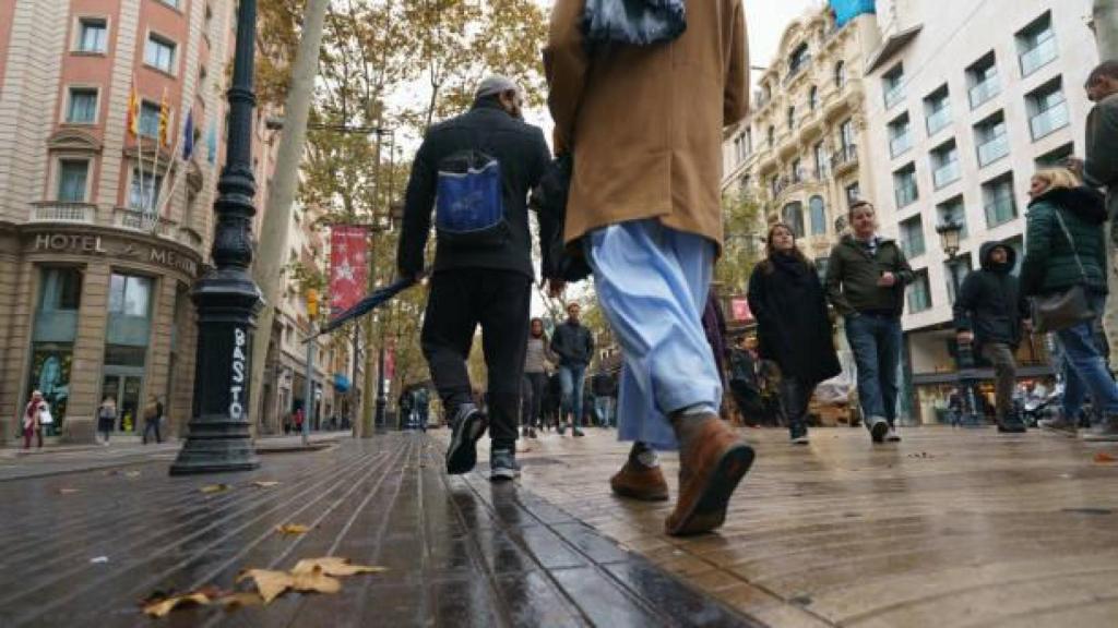 Varios transeúntes en una de las calles de Barcelona bajo la lluvia