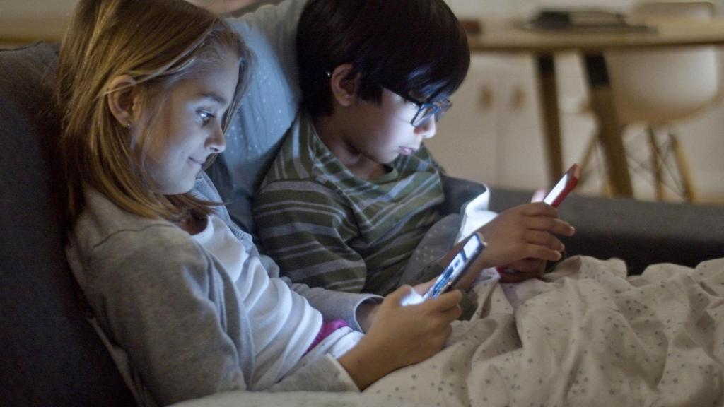 Un niño y una niña mirando el móvil