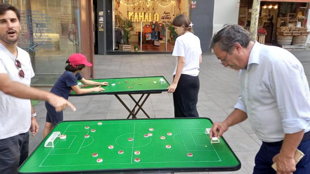 Aficionados jugando a fútbol botones en la plaza del Diamant