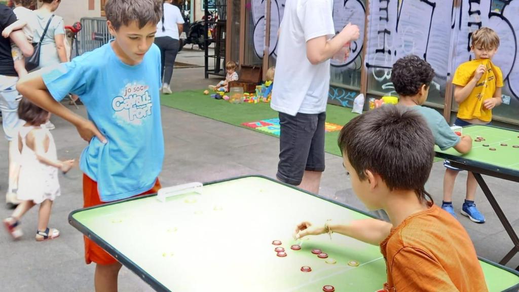 Niños jugando a fútbol botones en la plaça del Diamant