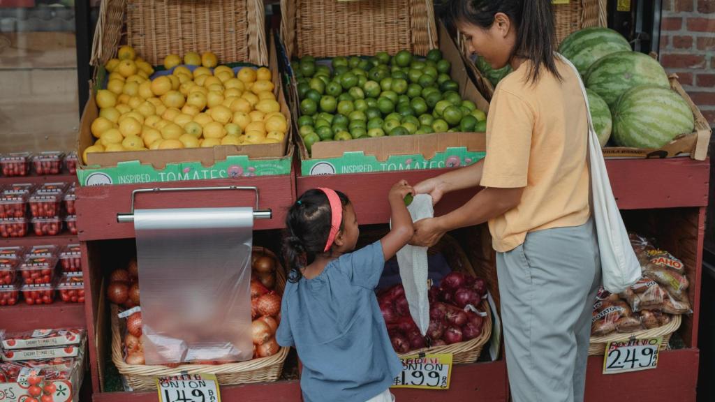 Una madre y su hija compran frutas en el mercado