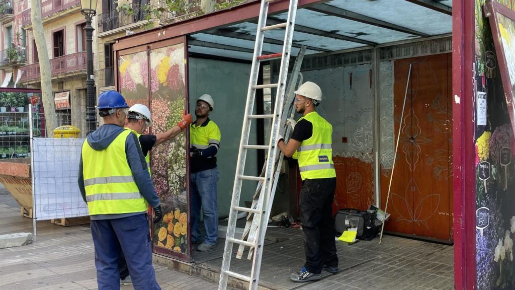 Operarios desmontan una parada de flores de La Rambla de Barcelona