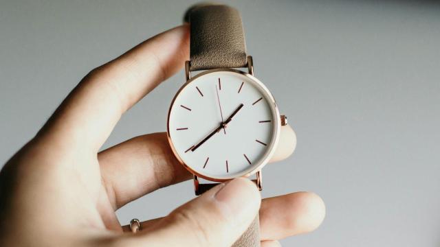 Una persona sostiene un reloj que marca la hora