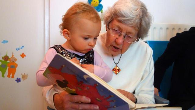 Una abuela leyendo un cuento a su nieta | CANVA