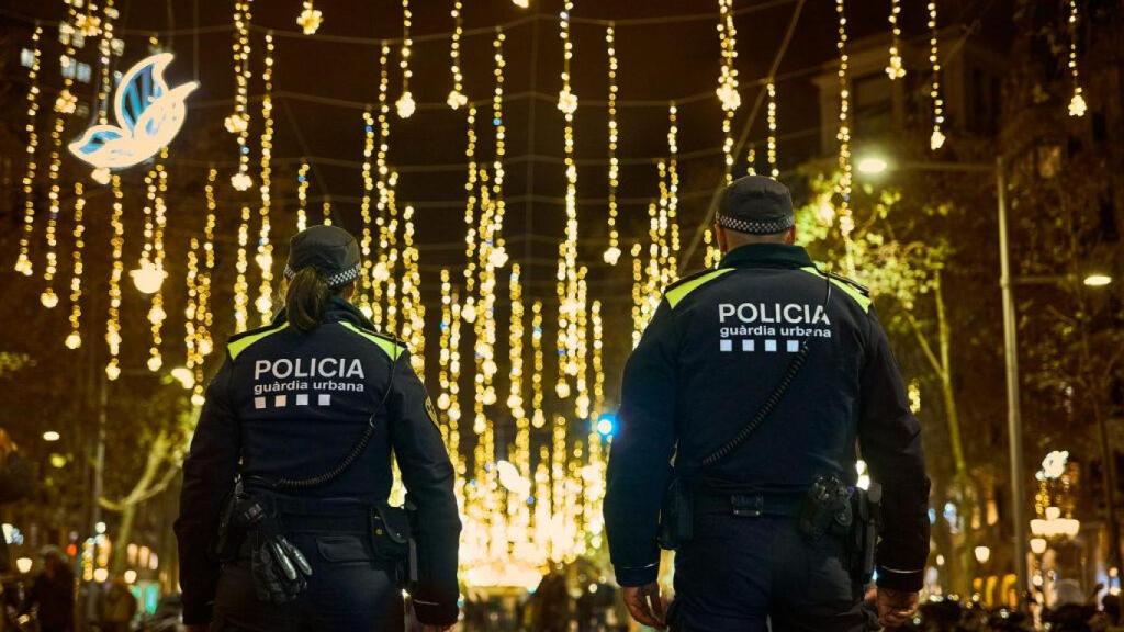 Dos agentes de la Guardia Urbana en paseo de Gràcia con las luces de Navidad de fondo