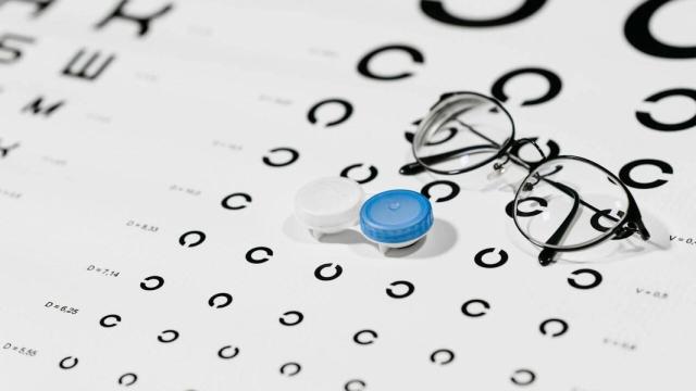 Gafas y bote de lentillas sobre una hoja de prueba de visión