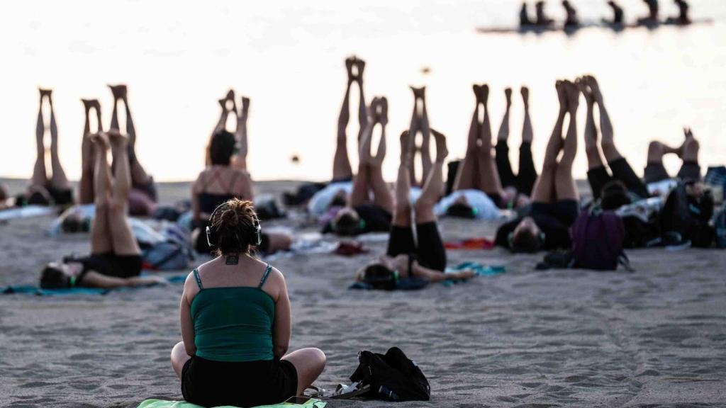 Un grupo de internacionales residentes en Barcelona medita en la playa de Sant Sebastià de Barcelona