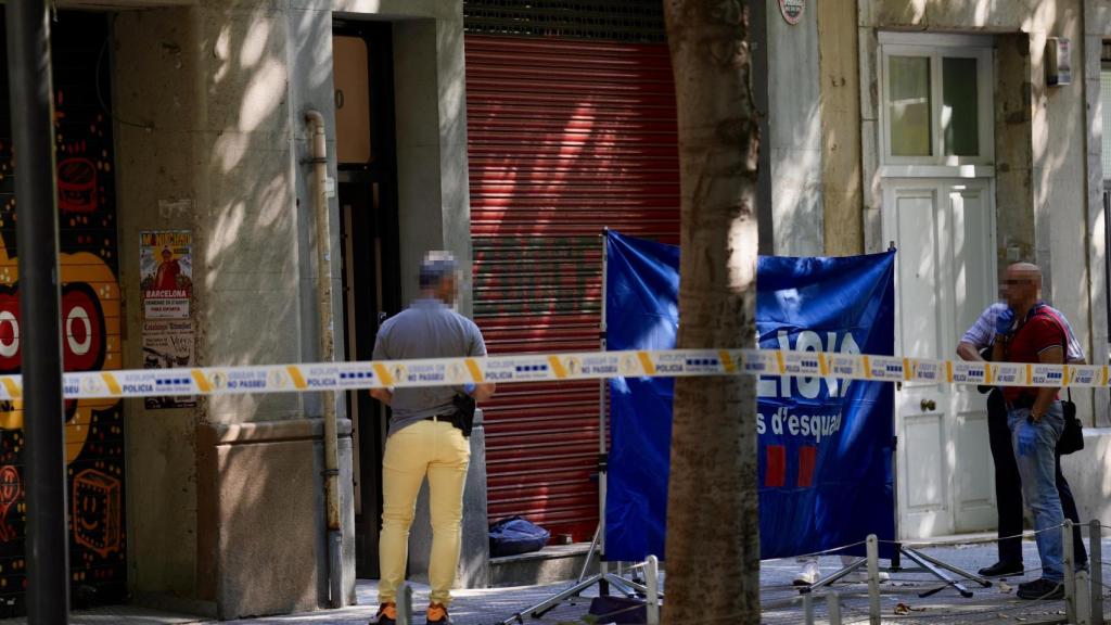Agentes policiales frente al portal de Consell de Cent en el que han matado de un tiro en la cabeza a una persona